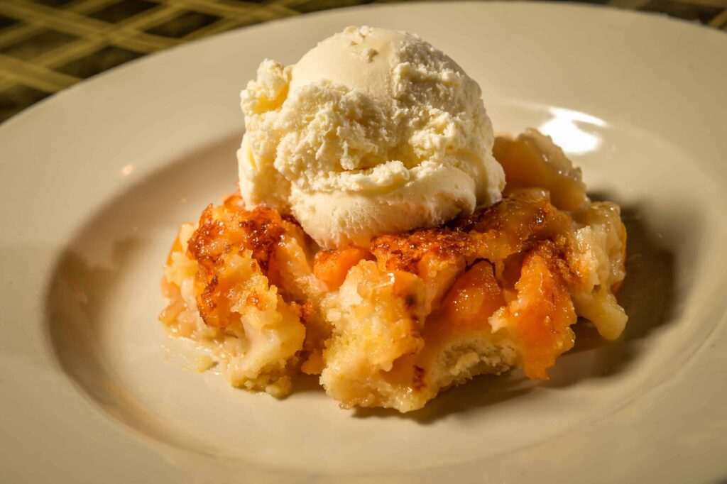 A bowl of cobbler topped with a scoop of vanilla ice cream.