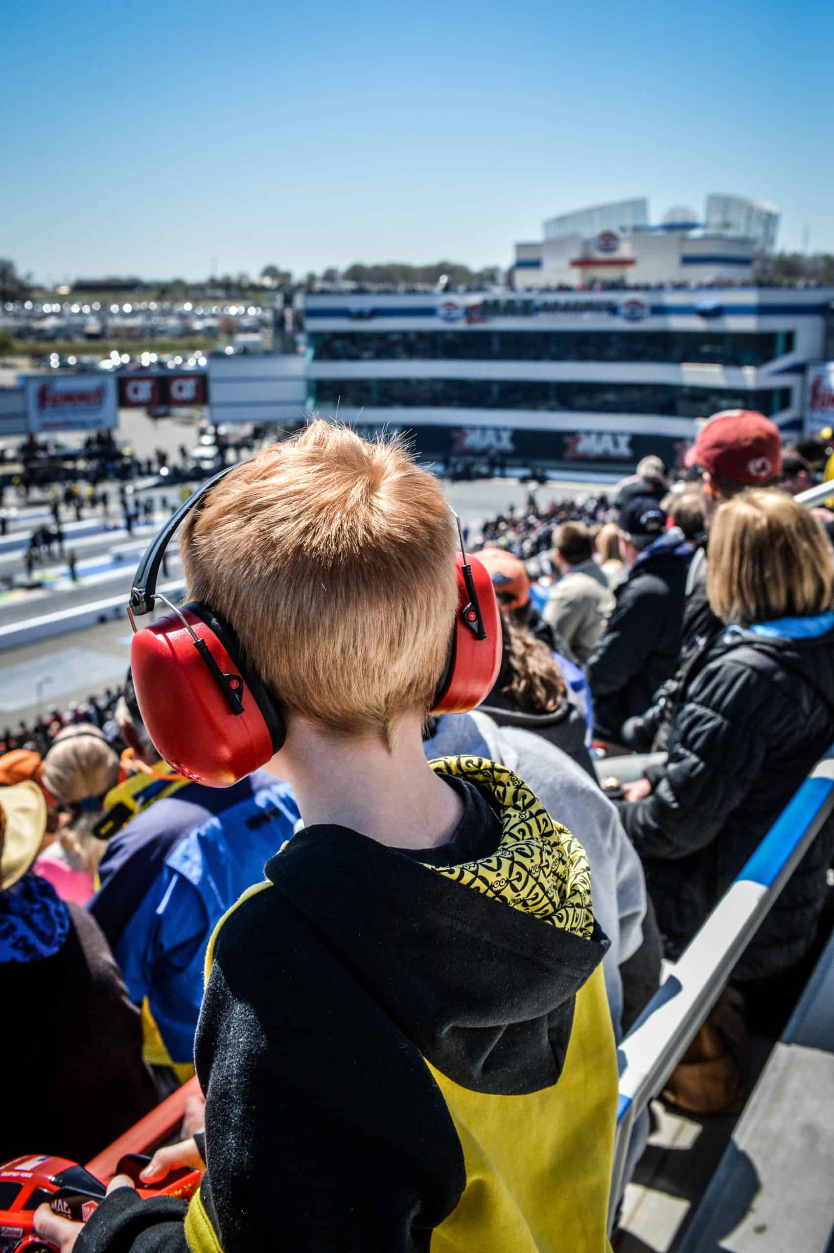 Young race fan with ear protection on enjoys drag racing at zMAX Dragway