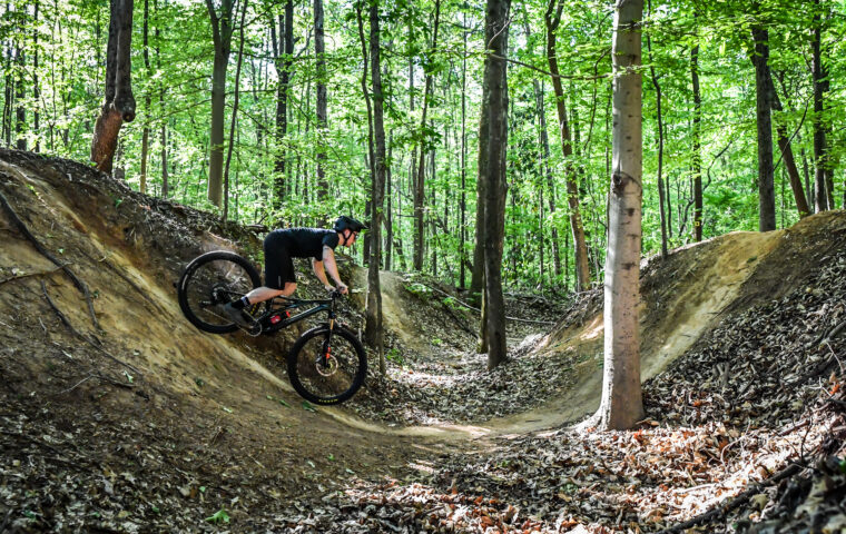 person riding bike through dip on trail