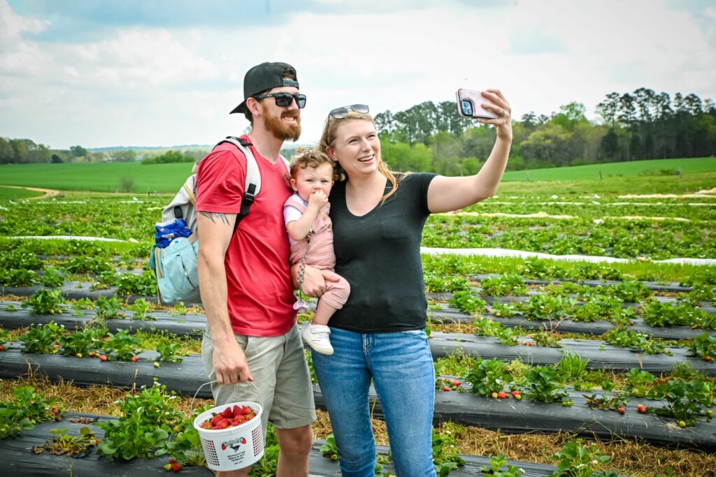 family takes a selfie picture in a strawberry field