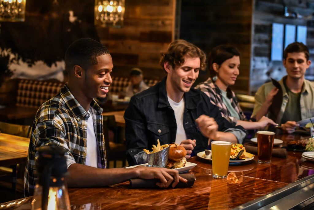 three people enjoying food at a bar