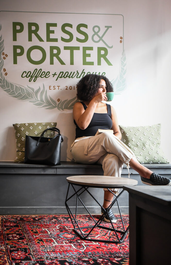 woman sipping coffee and holding a book while looking out a window