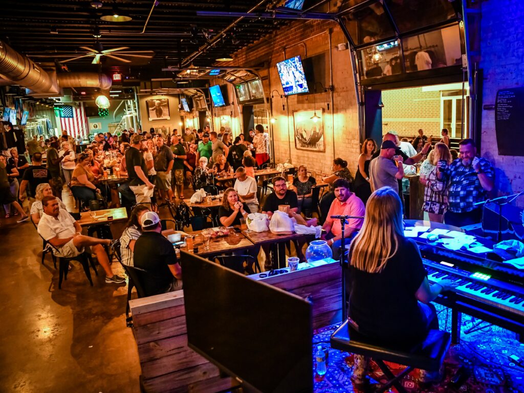 woman plays piano inside brewery filled with spectators