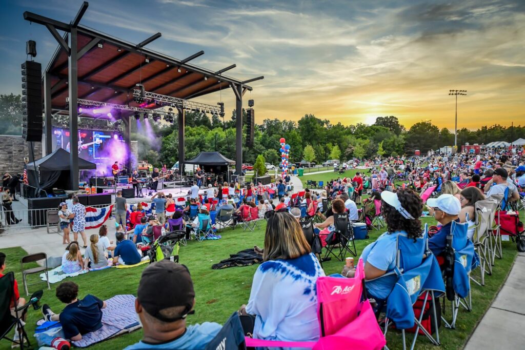 crowd gathered in front of amphitheater stage as live band performs