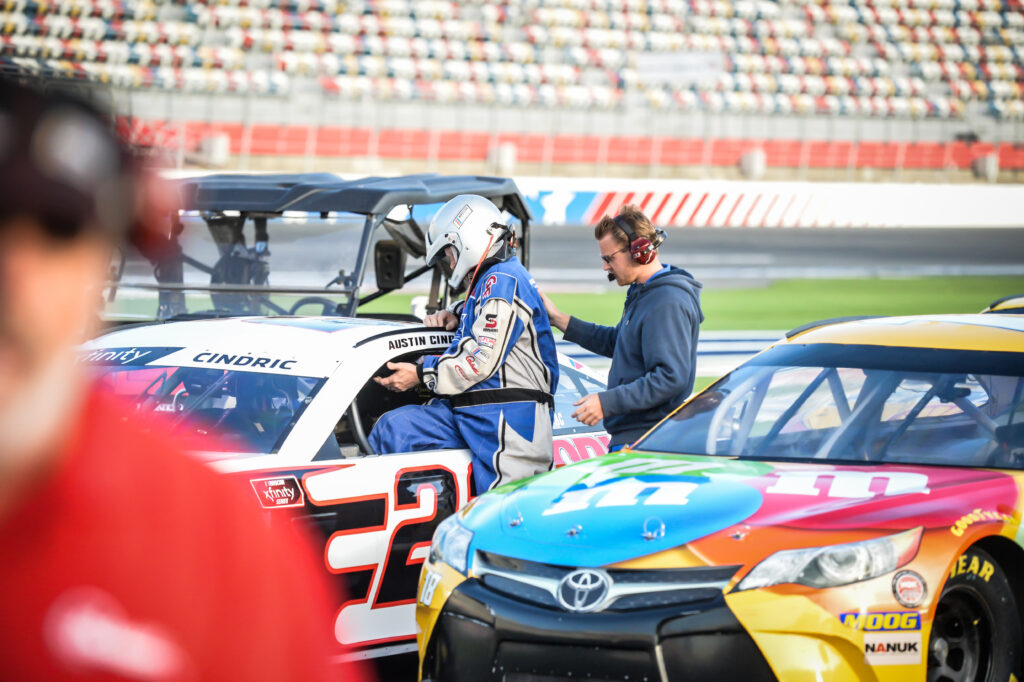 instructor assists driver getting into race car